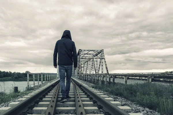 Un hombre camina por el viejo puente del tren sobre un río . — Foto de Stock