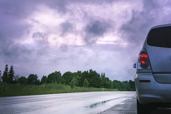 Auto on the road under a stormy sky.