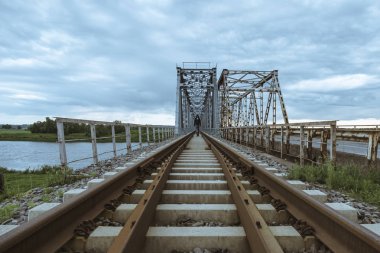 Bir adam eski tren Köprüsü bir nehir üzerinde yürür..
