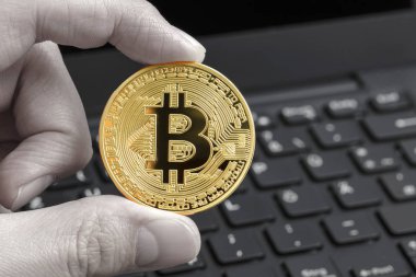 Altın bitcoin içinde siyah ve beyaz dizüstü klavye arka plan ile parmak. Kripto para kavramı.