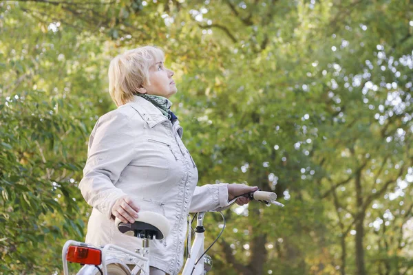 Active happy carefree smiling senior woman ridding bike in autumn nature. — Stock Photo, Image