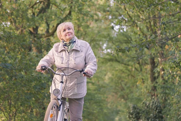 Activa feliz sin preocupaciones sonriente mujer mayor de montar en bicicleta en la naturaleza de otoño . Imágenes de stock libres de derechos