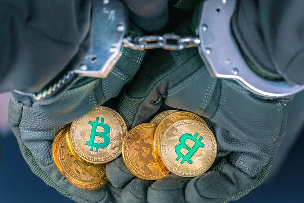 Puños arrestados esposas manos sostienen bitcoins de oro . Fotos de stock libres de derechos