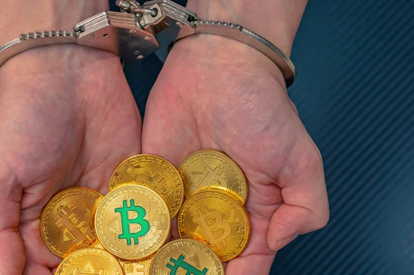 Las manos esposadas detenidas sostienen un bitcoins de oro . Imagen de stock