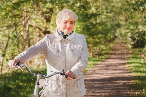 Ativo feliz despreocupado sorrindo sênior mulher livrando bicicleta no outono natureza . Imagens Royalty-Free
