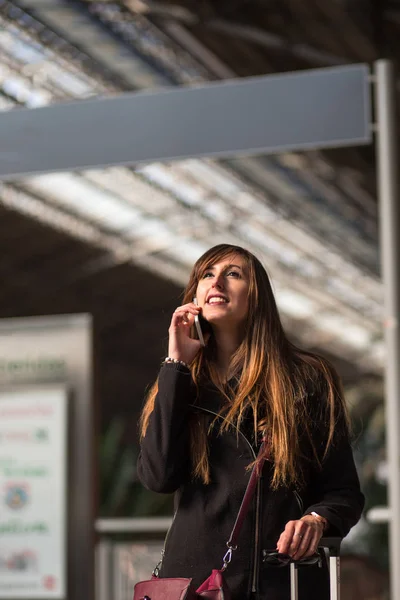 Jovem mulher falando ao telefone em uma estação — Fotografia de Stock