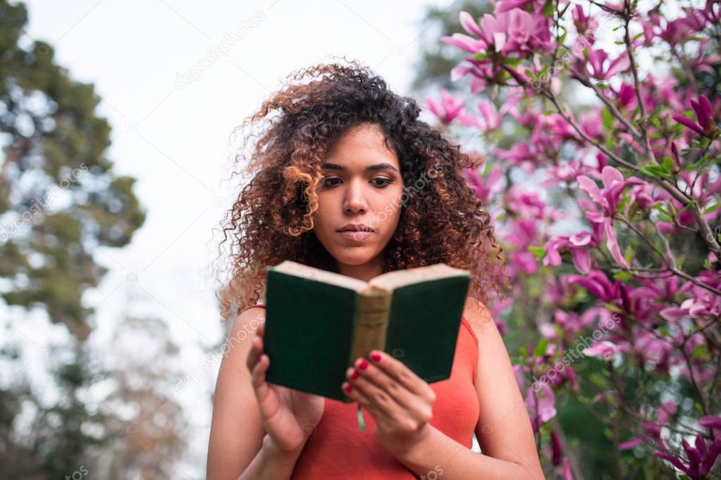 afro woman reading a book outdoors