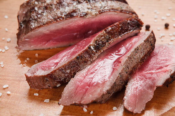 Thick slices of superior grilled meat served on wooden table, close up view. Restaurant menu photo. Gourmet concept