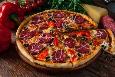 Taze pizza koyu ahşap masanın üzerine dilimler halinde kesin