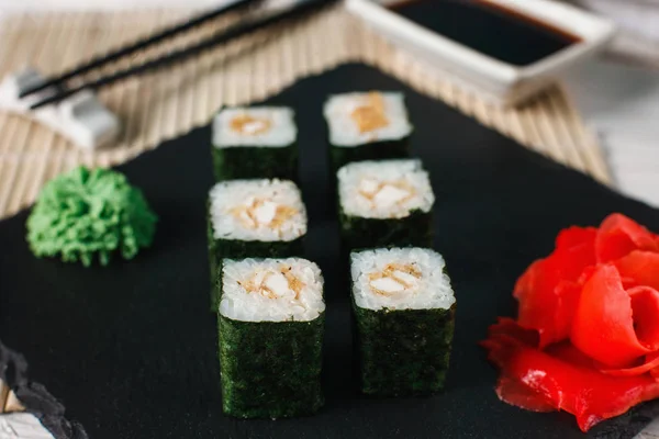 Deliziosi involtini di sushi freschi serviti su ardesia nera — Foto Stock