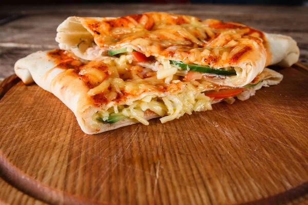 Кусочки пиццы кальцоне на деревянной тарелке, крупный план — стоковое фото