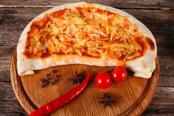 Pieczone pizza calzone z serem na drewnianym stole — Zdjęcie stockowe