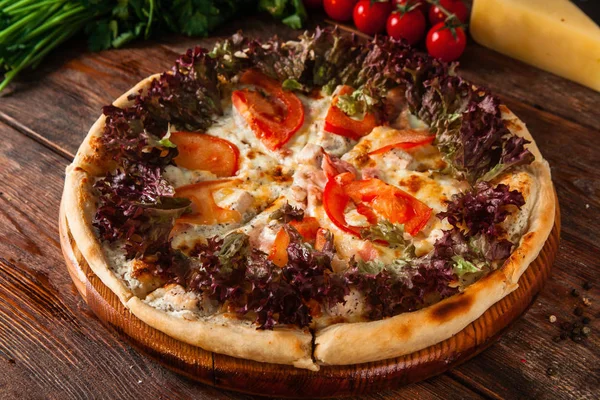 Pizza with tomatoes and basil on rustic wood table