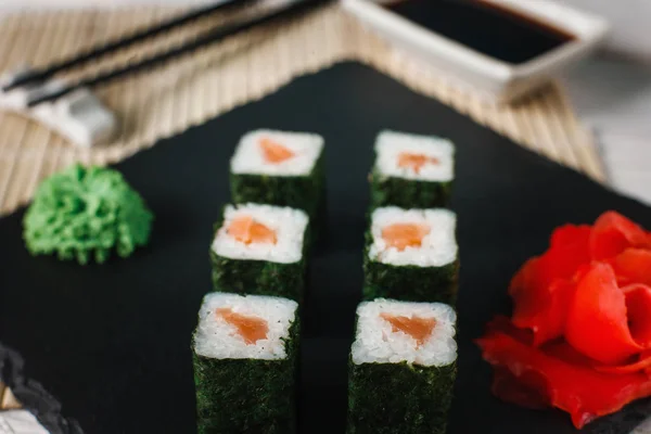 Involtini di sushi con salmone servito su ardesia nera — Foto Stock