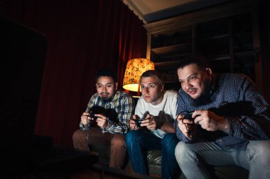 Three concentrated young guy play home video game clipart