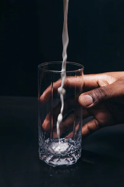 Leche verter al vaso en mano de hombre negro, primer plano — Foto de Stock