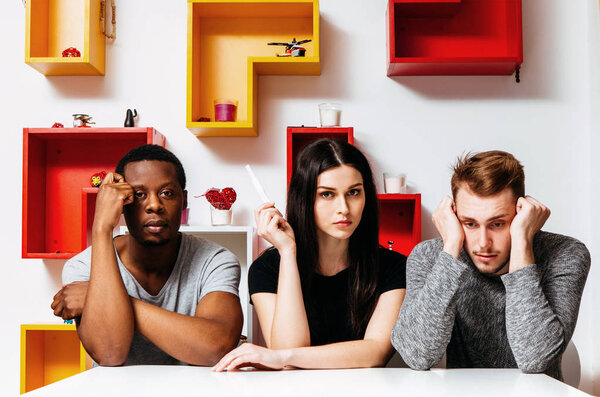 Женщина с тестом на беременность и ее два партнера
