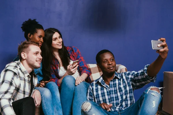 Cuatro amigos felices hacen selfie de grupo con móvil — Foto de Stock