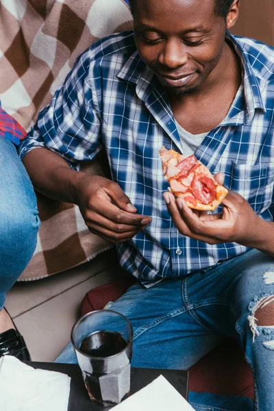 Hombre negro comer pizza con soda en casa, primer plano — Foto de Stock