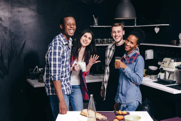 Cuatro hombres y mujeres jóvenes se divierten en la cocina casera — Foto de Stock