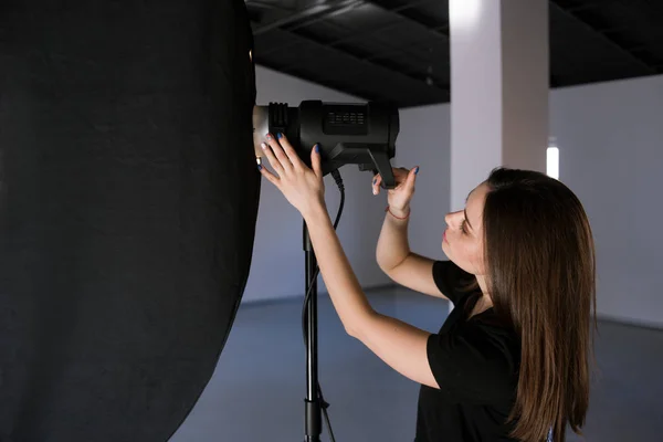 Asistente de fotógrafo ajustar la luz en el estudio — Foto de Stock