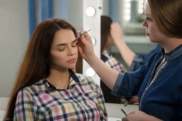 Maquillaje artista arranca las cejas al cliente — Foto de Stock