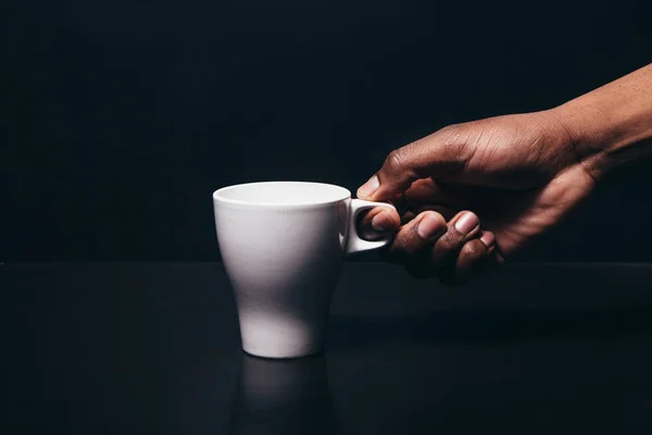 Negro hombre mano tomar blanco taza, oscuro fondo — Foto de Stock