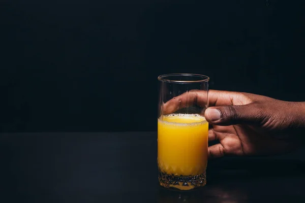 Mano negra con vaso de zumo de naranja, espacio libre — Foto de Stock