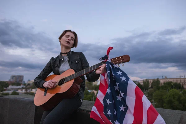 Певица с флагом США, играющая на гитаре — стоковое фото