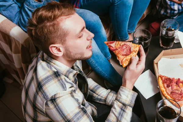 Joven comer pizza en casa en compañía de amigos — Foto de Stock