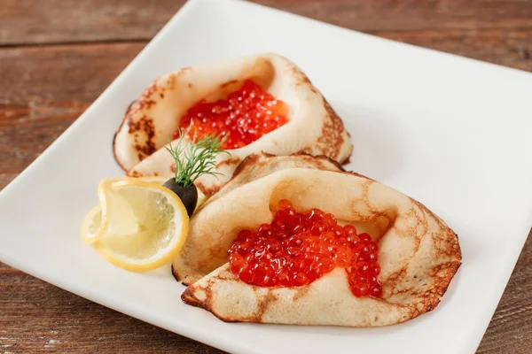 Panquecas com caviar vermelho na placa branca — Fotografia de Stock