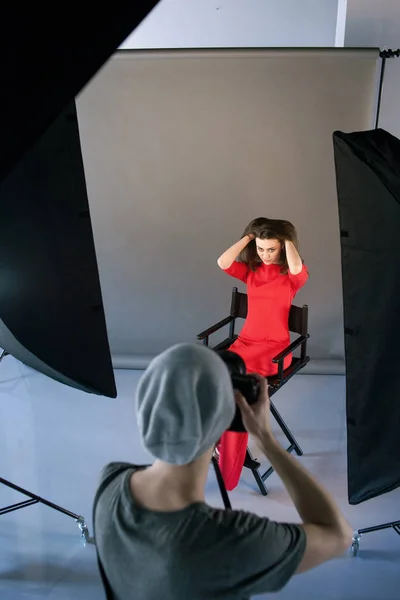 นักถ่ายภาพถ่ายแบบในชุดสีแดงที่สตูดิโอ — ภาพถ่ายสต็อก