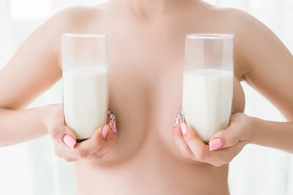 Dos vasos de leche parcialmente cerrar pechos de mujer —  Fotos de Stock