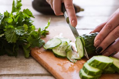 Kadın salatalık ahşap masanın üstüne keser.