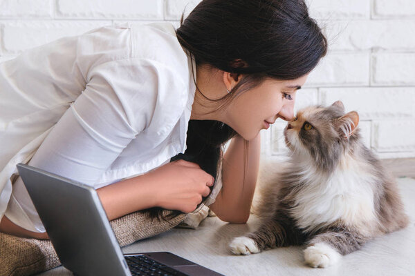 Young woman and her lovely cat rubbing noses