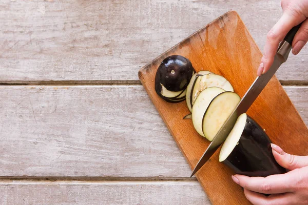 Donna fette di melanzana su scrivania di legno — Foto Stock