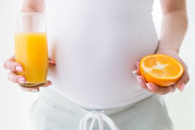 Hamile kadının elinde taze portakal suyu