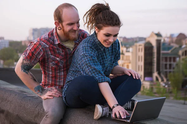 Hipster couple on roof with laptop