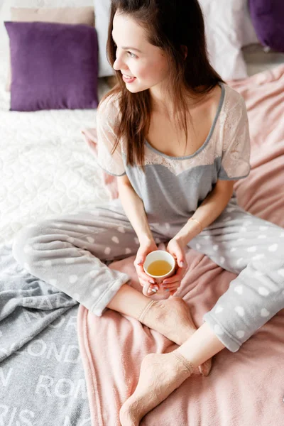 Gülümseyen genç kadın şefkatle çay tutar