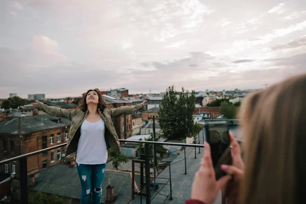 One girl makes photo of her friend on roof — Stock Photo, Image