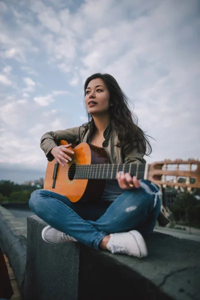 Free music. Female guitarist plays on the street.