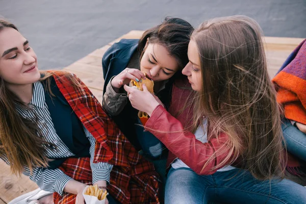 ハンバーガー 1 つを共有する 2 人の女の子。緊密な友好関係 — ストック写真