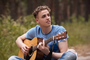 Gülümseyen adam gitar orman kavramı oynamak.