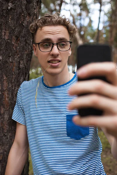 Sonrisa hombre guapo selfie teléfono bosque concepto . — Foto de Stock