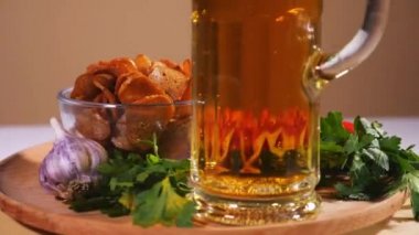 Ekmek kraker, pastırma, kiraz domates ve sebzeli bir tabakta bir bardak bira.
