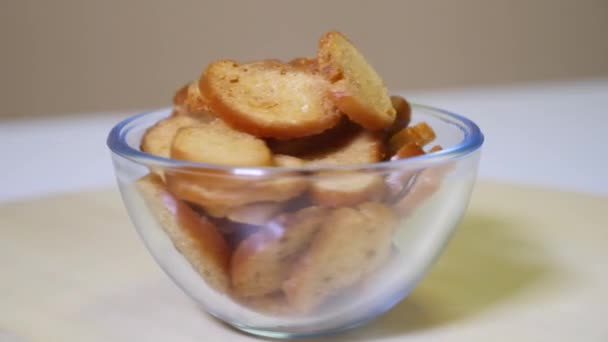 Вкусные хлебные крекеры в стеклянной чаше на вращающейся деревянной платформе — стоковое видео