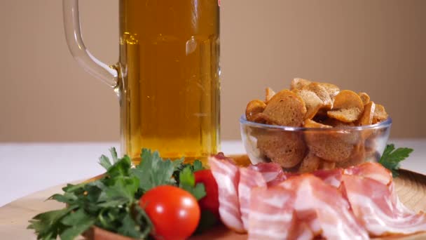 Вкусные хлебные крекеры, бекон, помидоры черри и стакан пива — стоковое видео