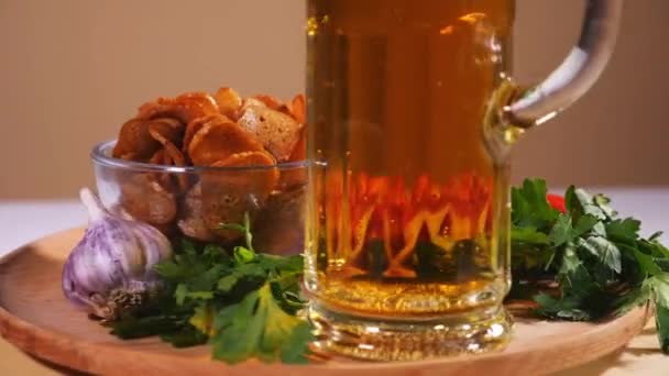 Стакан пива на тарелке с хлебными крекерами, беконом, помидорами черри и зеленью — стоковое видео