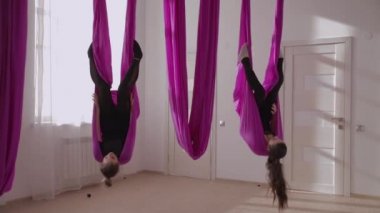 Hava yogası. İki kız baş aşağı asılı.
