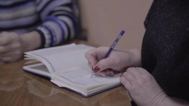 Ofis çalışanları masada oturuyor, bir kadın organizatörde bir şeyler yazıyor..